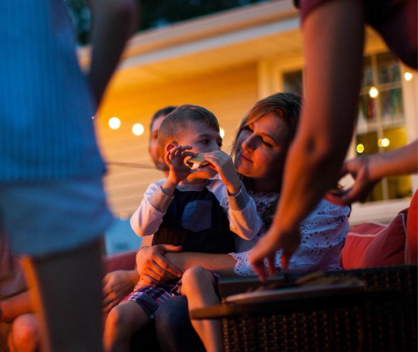 Mother holding her son eating smores in backyard gathering