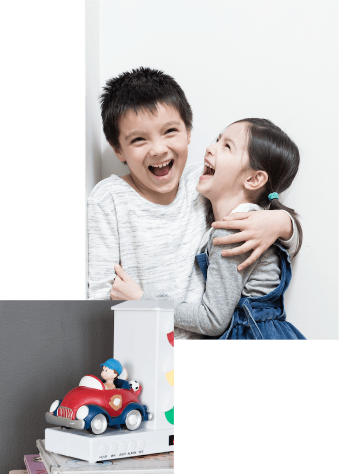 Siblings hugging each other next to a toy car