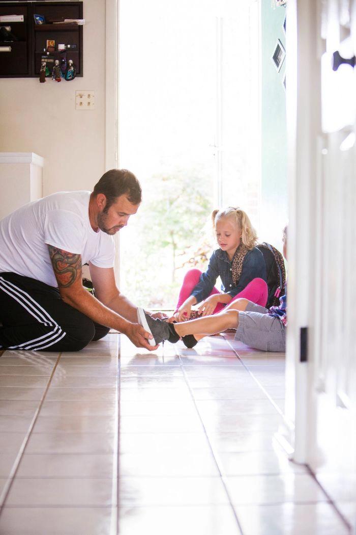 A father tying his children's shoes
