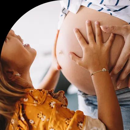 A child excitedly touches a pregnant belly