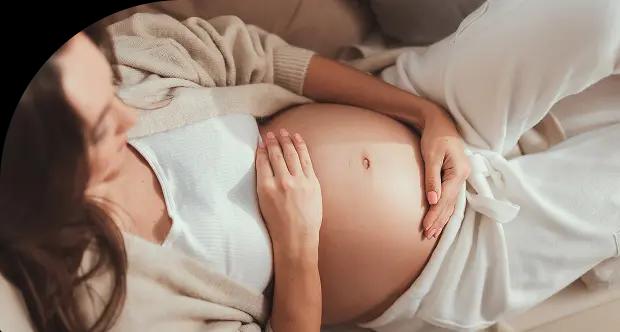 Pregnant woman lying down, gently holding her belly