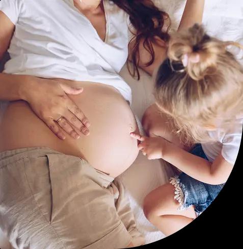 Pregnant woman's belly with a small child pointing at it