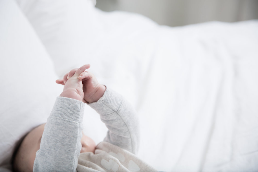 Picture of baby on bed holding its hands up