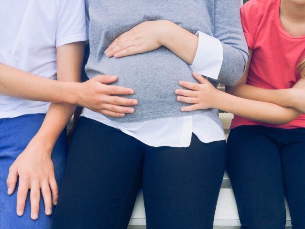 A pregnant woman touching her belly.